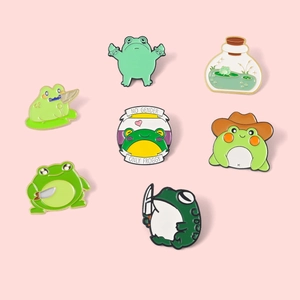 Set of funny cartoon green frog enamel pins with cute knife and bottle designs