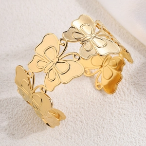 Close-up of golden stainless steel cuff bracelet with hollowed leaf and butterfly details