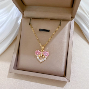 Close-up of heart pendant with pink bow zircon and tiny white diamonds in a jewelry box