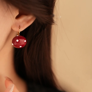 Detail view of red polka dot earring with gold hoop on model showing elegant vintage style