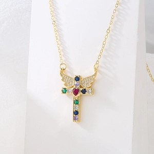 Exquisite gold cross necklace with wings and colorful gems on white mannequin stand