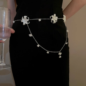 Detail of silver chain belt with white flowers and pearls worn on a black dress