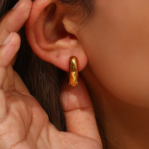 Close-up of a minimalist 18K gold plated stainless steel heart huggie hoop earring on ear