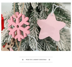 Close-up of pink wooden snowflake and star ornaments hanging on a snowy Christmas tree