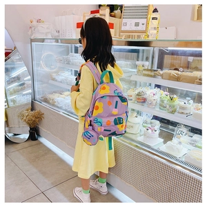 Girl wearing a purple floral children's backpack with matching mini coin purse detail