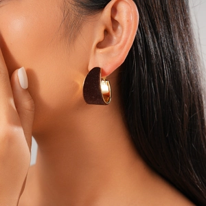 Close-up of model wearing wide C-shaped velvet earrings with gold metal inner lining