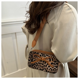 Fashionable leopard print crossbody bag with bow detail worn over a beige coat