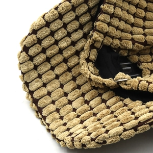 Macro detail of brown popcorn textured knit fabric on a thick winter baseball cap
