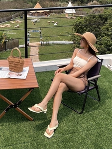 Detail of a large straw hat with fringe edge and beach vacation outfit in nature