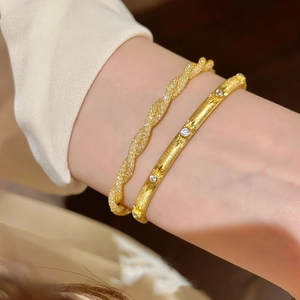 Detailed close-up of a gold-tone twisted rope bracelet and a starburst gemstone bangle set