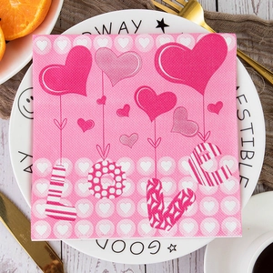 Pink heart patterned napkins with LOVE text displayed on a table for Valentine decor
