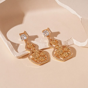 Detail of gold hollow rose pattern inside a gourd-shaped earring with zircon studs