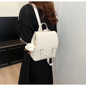 Détail du sac à dos en cuir crème avec imprimé ours et porte-clé nuage en peluche
