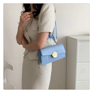 Détail du sac bandoulière bleu clair avec fermoir doré et poignée en tissu plissé doux