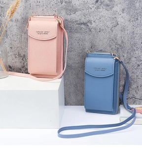 Detail view of pink and blue long wallets with crossbody straps and logo engraving