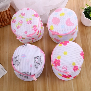 Four cylindrical mesh laundry bags with floral and cartoon bear prints on wood background