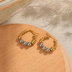 Two-tone beaded hoop earrings in gold and silver finish on a natural wooden display