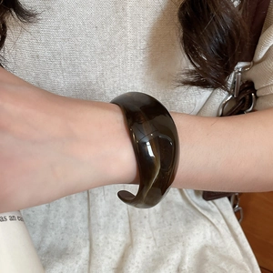 Close-up of translucent dark brown acrylic irregular open bangle on a model wrist