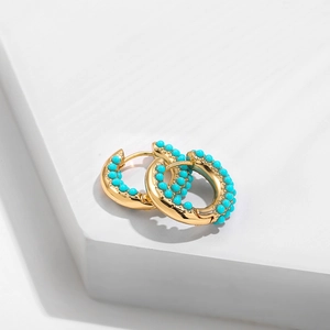 Detailed close-up of gold hoop earrings with inlaid turquoise beads on white background