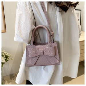 Detail view of woven lavender handbag with a large bow decoration and metal strap hooks