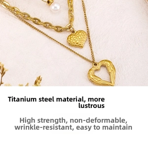 Detail of triple-layered titanium steel necklace with gold-plated heart and pearl charms