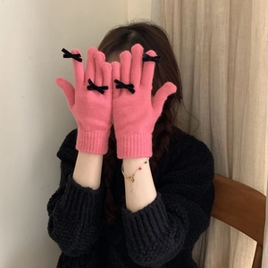 Detailed view of pink knitted gloves with three black bows on a soft woolen texture