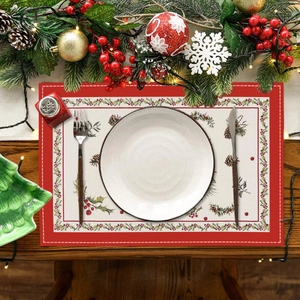Close-up of Christmas linen placemat with festive berry prints and white edge stitching
