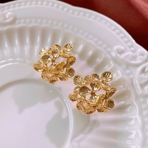 Macro shot of gold floral earrings on white embossed ceramic plate with vintage vibes