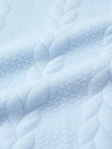Detailed macro view of light blue knitted fabric with intricate jacquard leaf textures