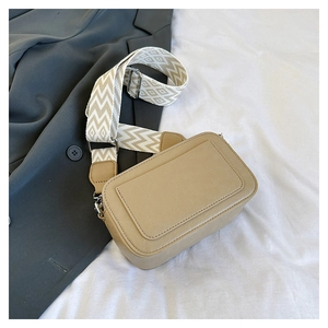 Detail of khaki leather crossbody bag with geometric pattern wide strap and silver hardware