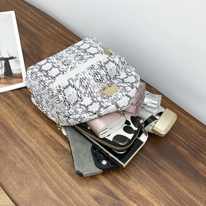Flat lay of small snake pattern backpack on wooden desk showing storage capacity
