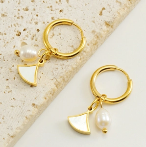Détail macro de créoles plaquées or 18K avec pendentif éventail et perle blanche