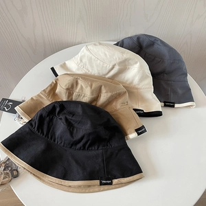 Close-up of four minimalist cotton bucket hats in neutral tones with adjustable chin cords