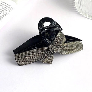 Detailed view of large black hair claw clip featuring a silver rhinestone bow decoration