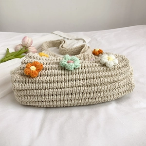 Minimalist knit handbag with 3D floral accents on a clean cream woven fabric