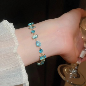 Macro detail of high-quality gold bracelet with blue geometric zircon crystals on model's wrist