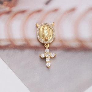 Detail view of gold Virgin Mary pendant with cubic zirconia cross on textured background