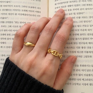 Detail of stacked gold knot and pig nose link rings on a vintage book background
