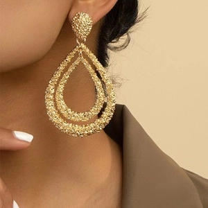 Detail shot of large gold-tone double teardrop earrings with hammered texture on ear