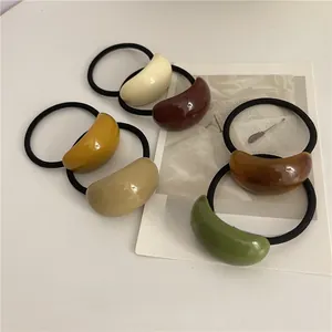 Detailed flat lay of Morandi color resin hair ties on a minimalist cream desk surface