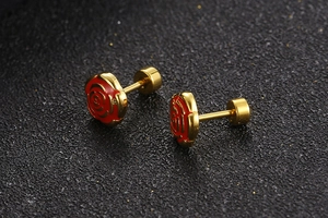 Close-up of gold-plated earrings with red enamel rose pattern on black frosted background