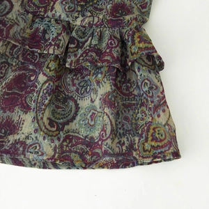 Detailed view of colorful paisley mini dress with gold metallic thread and ruffle trim