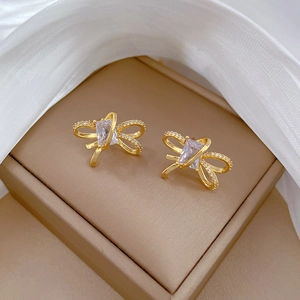 Macro shot of gold bow stud earrings featuring sparkling clear triangular cubic zirconia