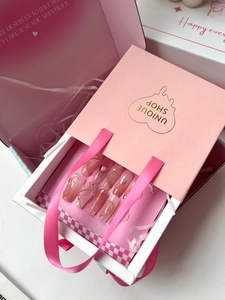 Détail d'ongles press-on dégradés roses avec strass en cœur dans un coffret cadeau luxe