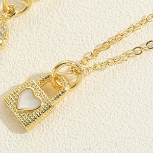 Macro view of gold heart lock pendant with white enamel center and beaded edge detail