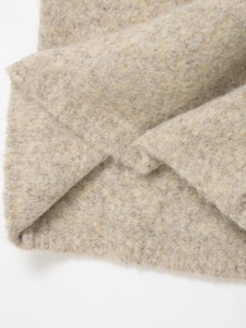 Gros plan sur un tricot beige chiné montrant les fibres de laine et les plis naturels