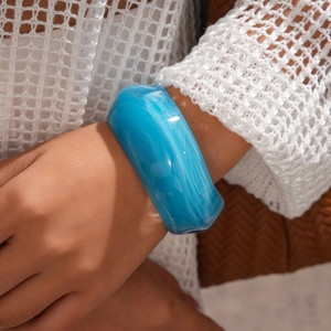 Detail of blue acrylic resin bangle with white cloud marble pattern on a female model