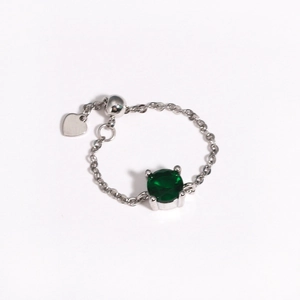 Detail of adjustable silver chain ring with green gemstone and heart pendant