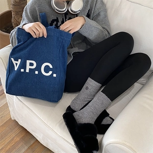 Navy blue denim tote bag with white V.P.C. lettering held by a model on a white sofa