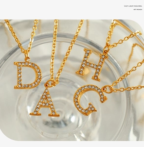 Detail of elegant gold-plated alphabet necklaces with sparkling crystal pavé pendants